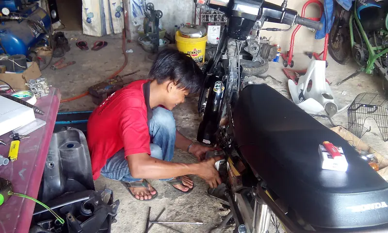 Mekanik memperbaiki motor di bengkel